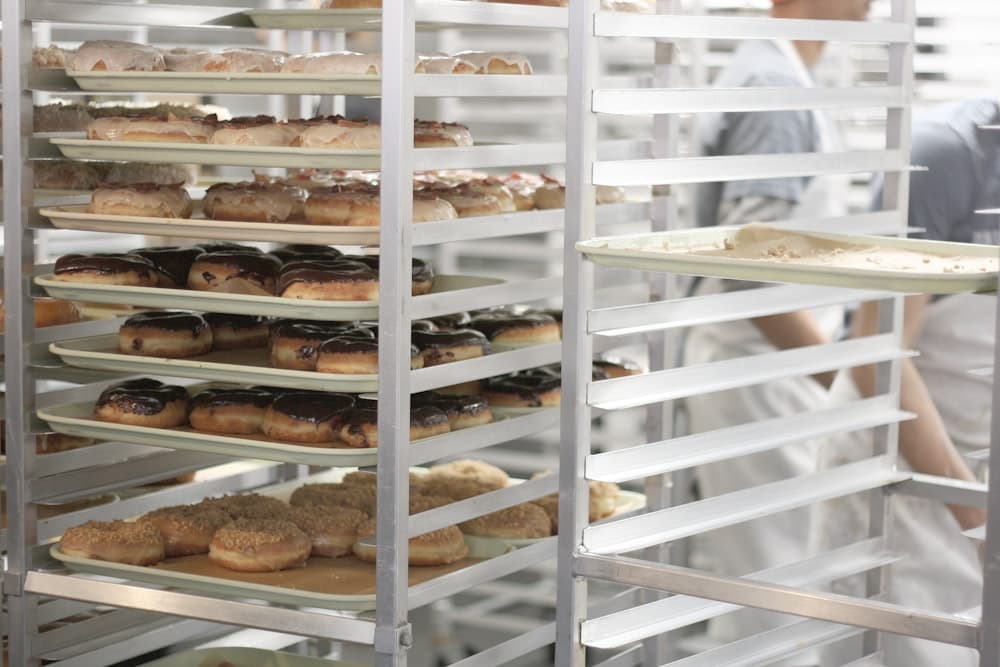 Trays of baked goods on a bakery rack, and a chilled retail display stocked with salad leaves