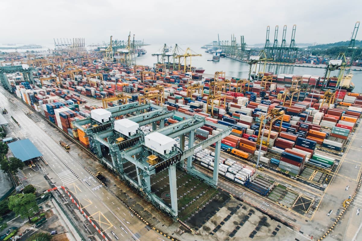 Aerial view of a container terminal, stacked boxes and quay cranes along the water