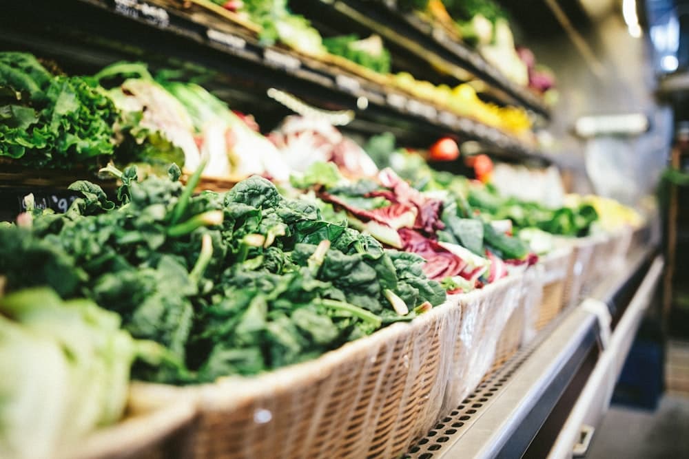 Trays of baked goods on a bakery rack, and a chilled retail display stocked with salad leaves